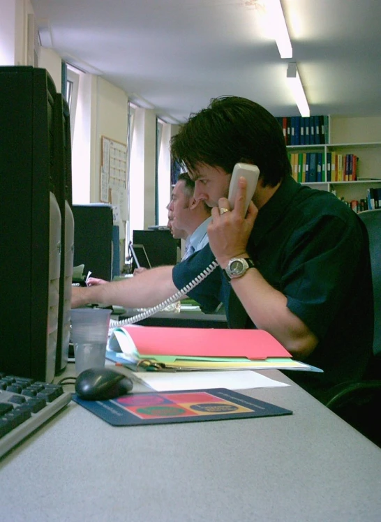 an office work place with people on cell phones and other electronic equipment