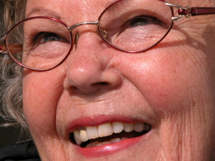 an old woman is smiling with glasses on