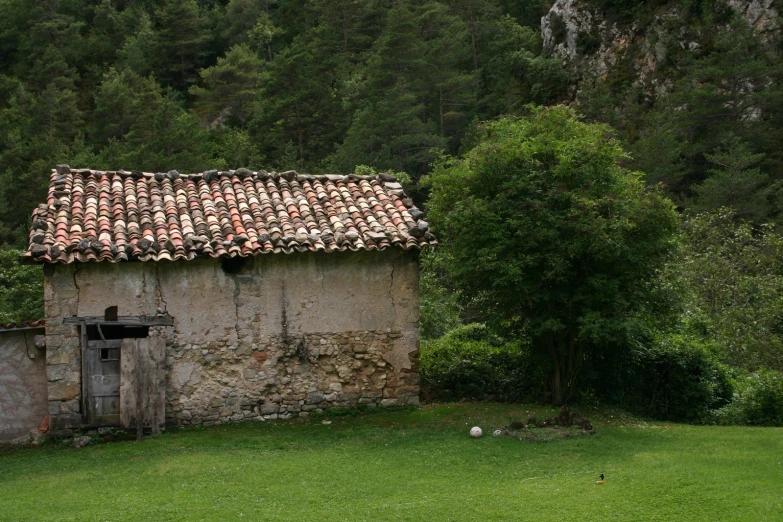 a stone building with tile roof surrounded by a forest