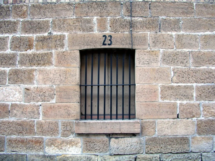 a prison barred window on the outside of a brick wall