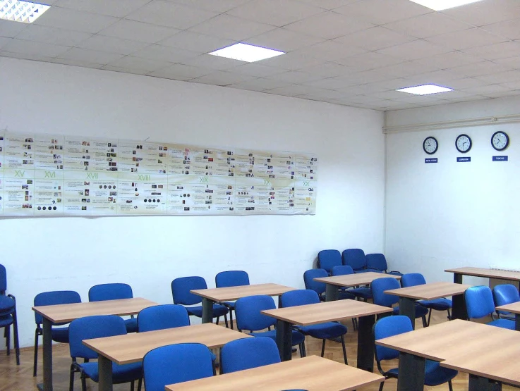 a large classroom with blue chairs and wooden tables