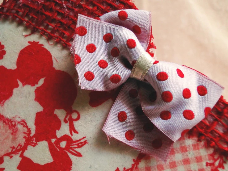 a red and white bow is resting on the fabric