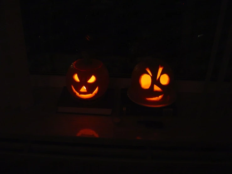 two pumpkins carved to look like faces sitting on a windowsill