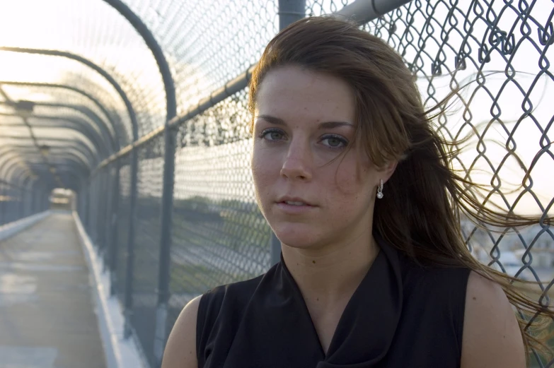 a girl with long hair standing in front of a fence