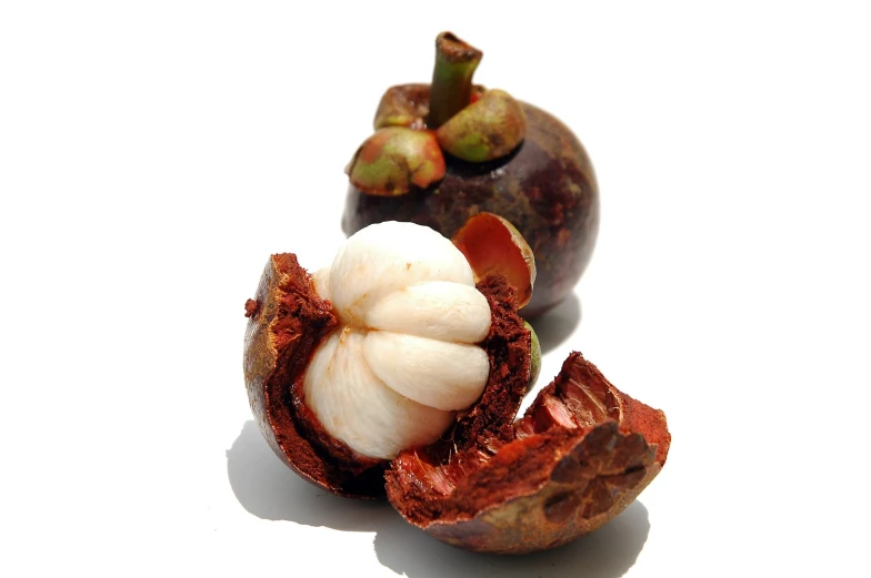 a peeled and cut fruit sitting next to it's open shell