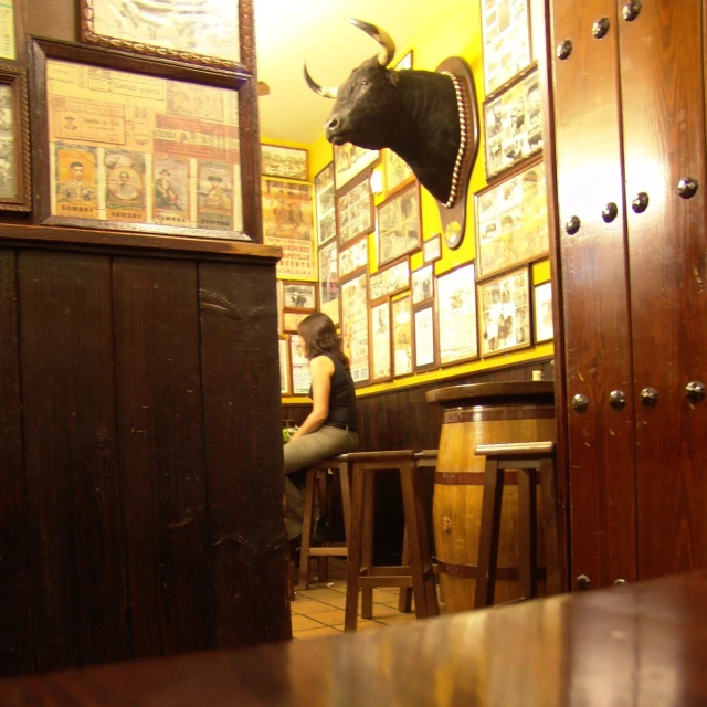 woman sitting at bar near taxi mask hanging above counter