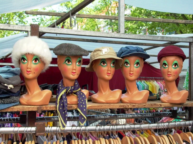 the mannequin heads are posed in a row in hats