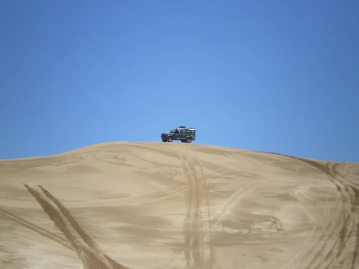 vehicle driving on the sand dunes against a clear sky