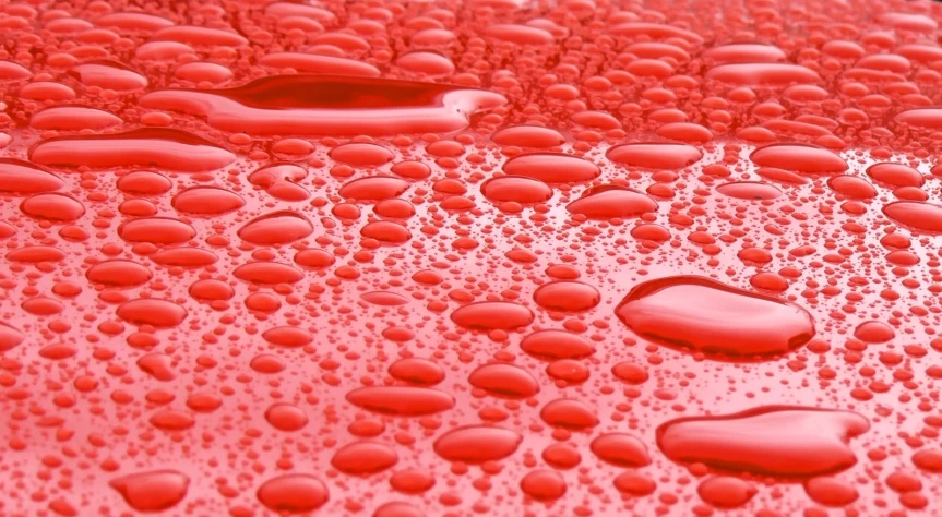 drops of rain on the hood of a red car