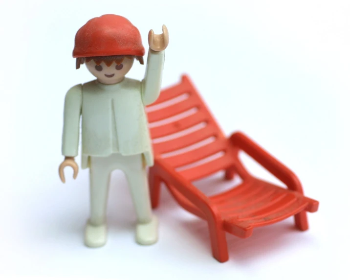 a toy is standing next to a miniature red chair