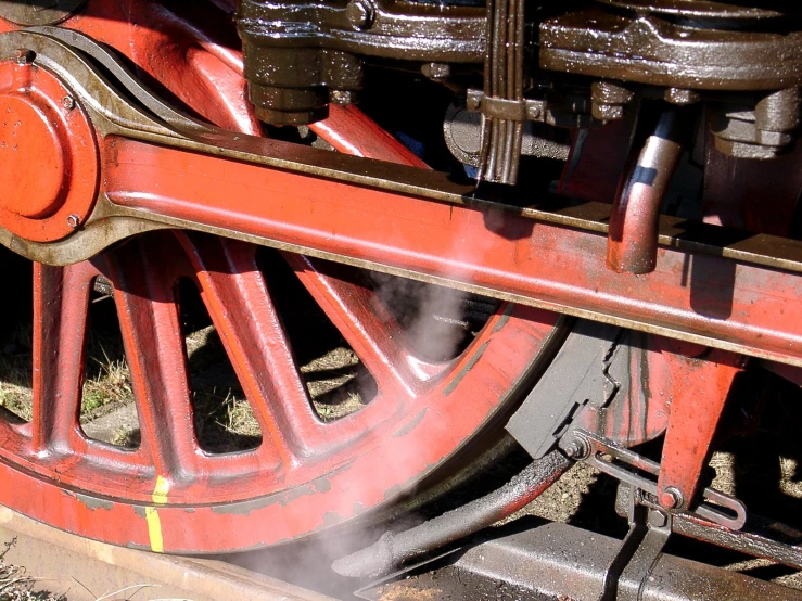 a red steam engine in motion with its wheels