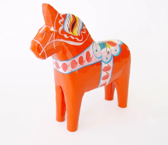 an orange ceramic horse with decorative designs is on a white surface