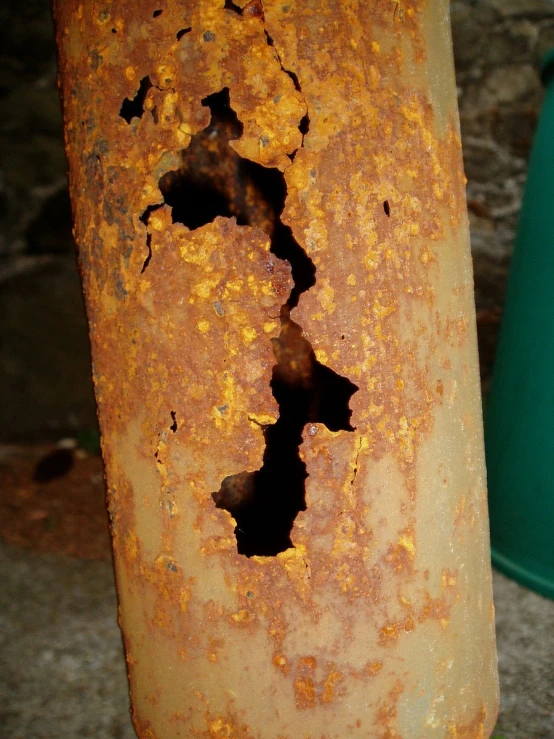 a rusted out vase sitting next to a green bucket