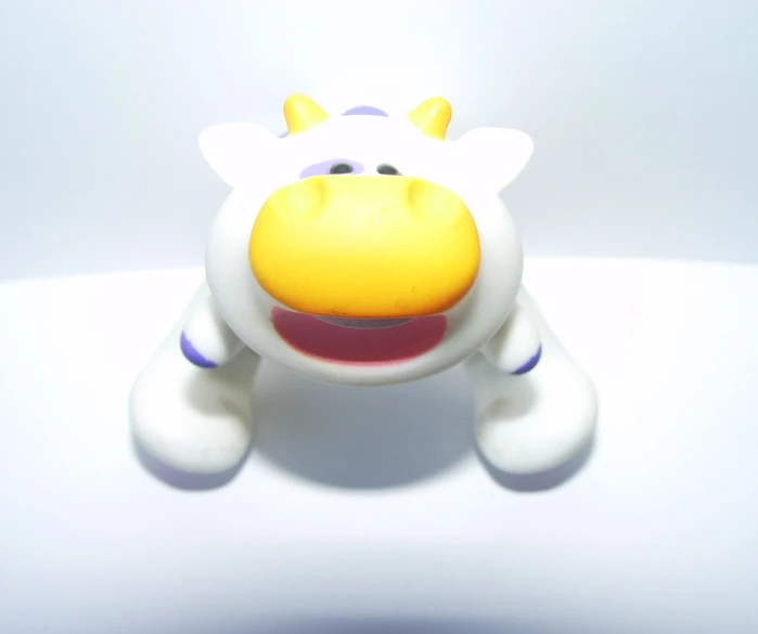 a white plastic cow with purple spots on it's face