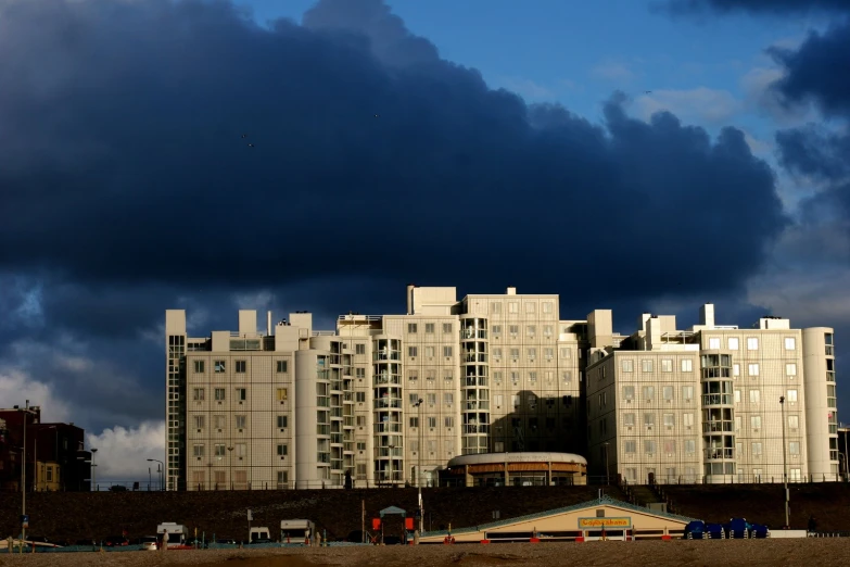 an apartment building on the beach with dark clouds in the sky