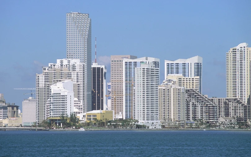 several skyscrs over water in a large city