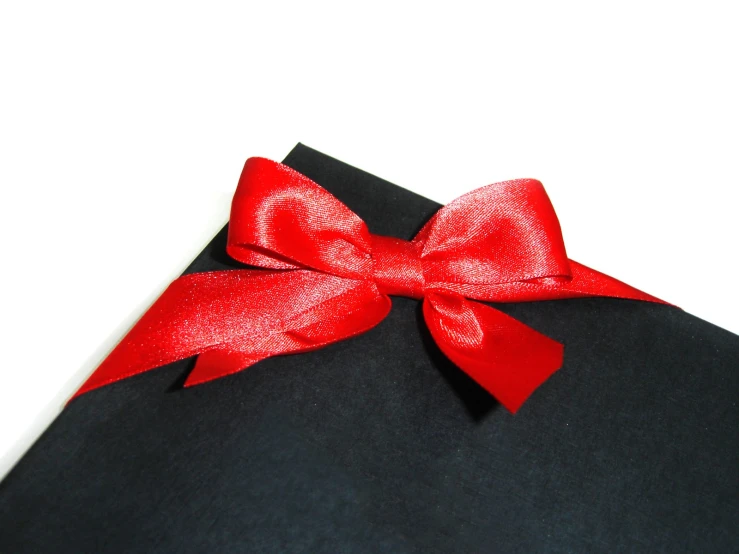 the corner of a black surface is tied with a bright red bow