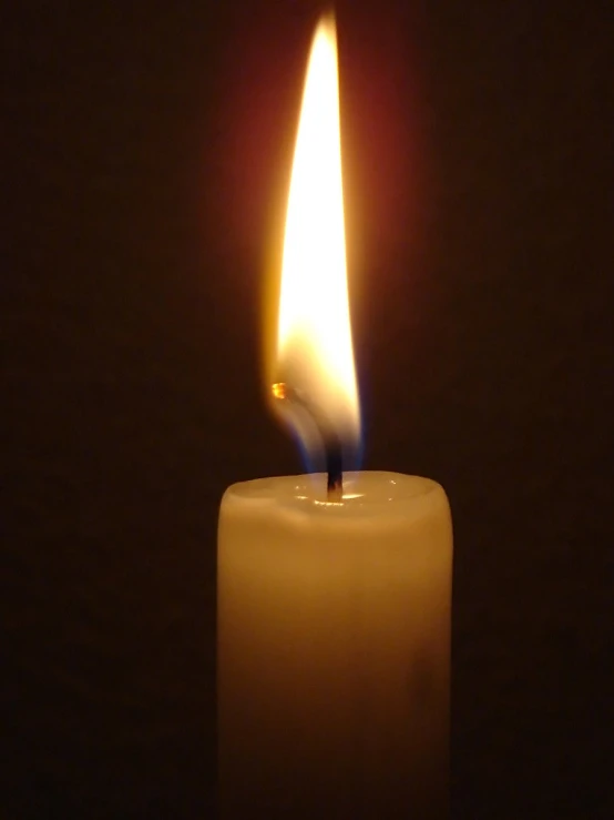 an lit candle sitting on top of a black background