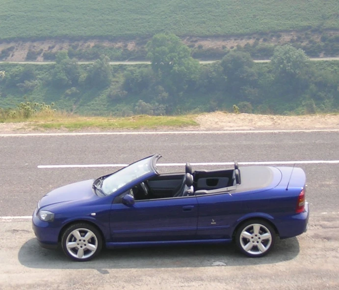 a blue convertible sports car parked on the side of the road