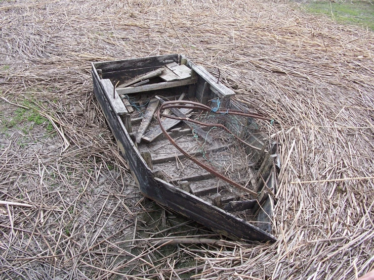 an empty old boat sitting in a dry field