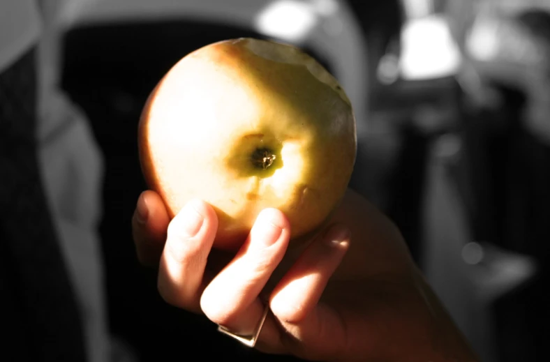 a hand holding a yellow apple up to the camera