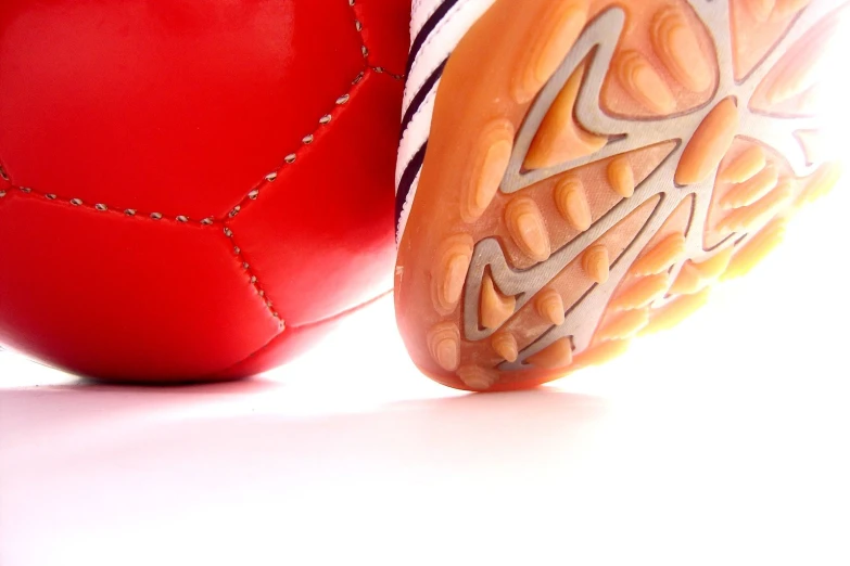 an orange ball and red basketball shoe against a white background