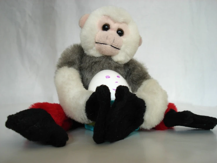 a stuffed monkey with a ball sits against the background