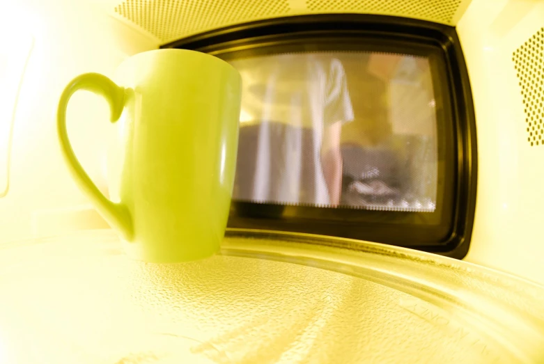 a coffee cup is on top of a microwave