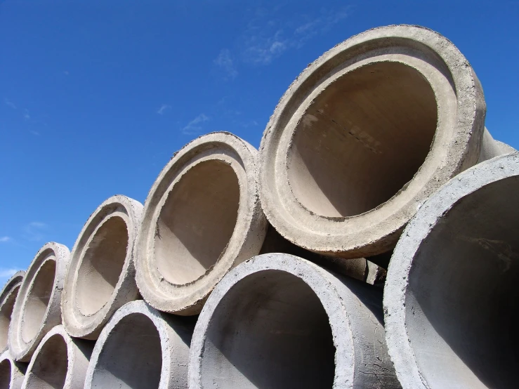 a stack of concrete pipes in rows under a blue sky