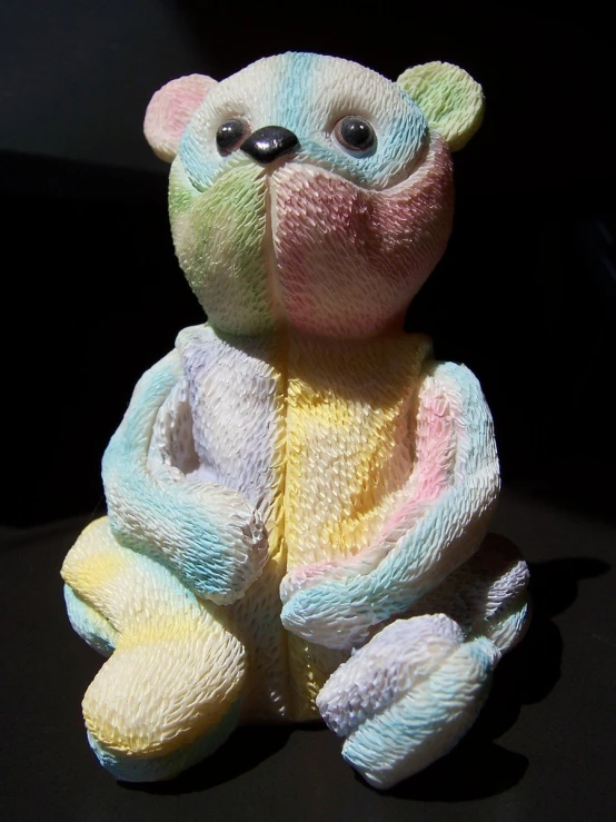 a stuffed bear is sitting down on a dark surface