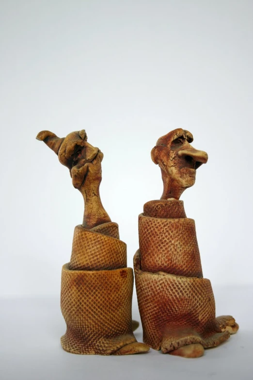 two wooden sculptures depicting camel heads and a giraffe head