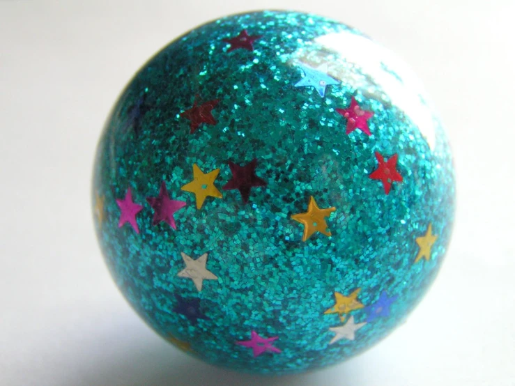 a shiny, green, speckled ball with gold and red stars on it