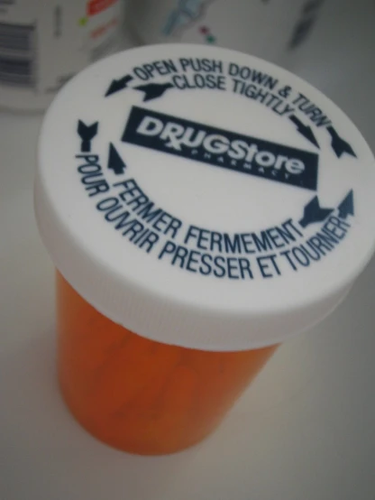 an open medicine bottle with the lid down and labels on it