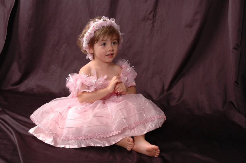 a small girl is wearing pink dresses and holding a flower