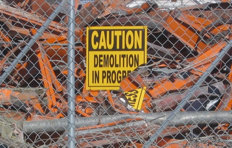 an orange and black sign in a fenced area
