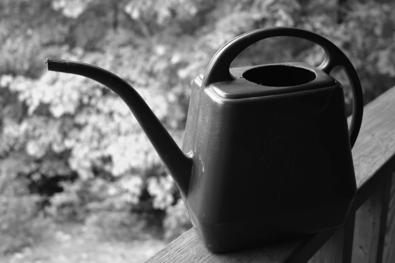 a plastic watering pot and pipe resting on a wood rail