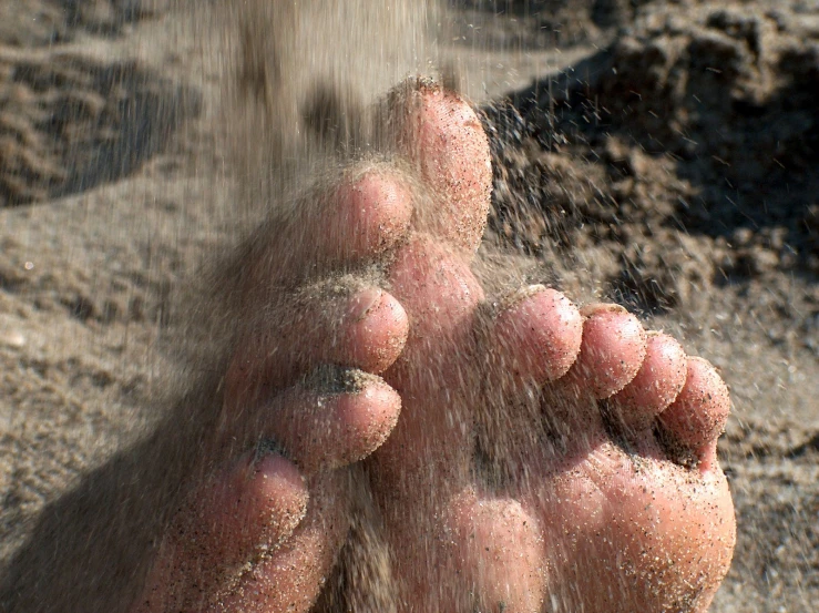 someone standing on the beach in the sand with their feet wet