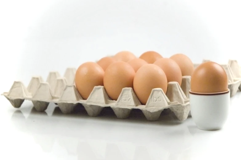 several eggs in an egg tray next to a mug