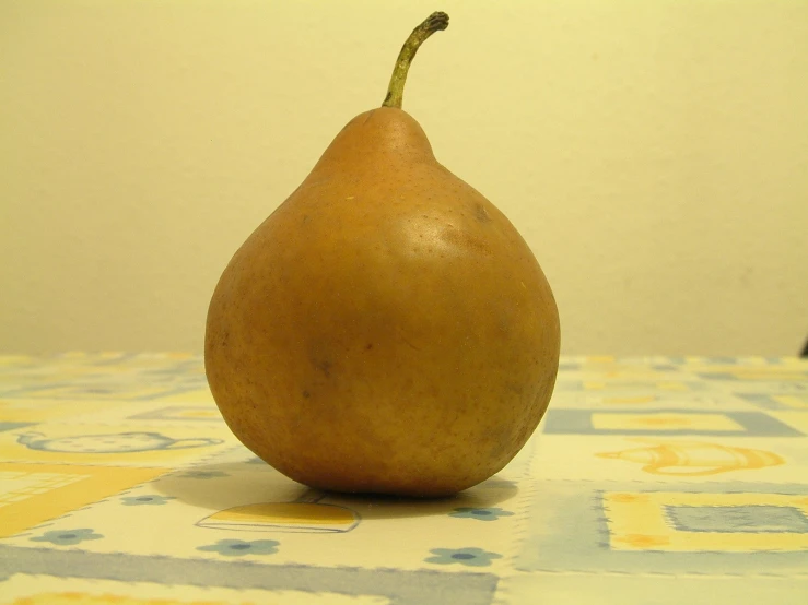 a small yellow pear on a blue and yellow tiled table
