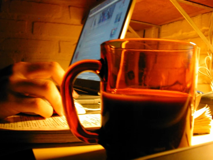 a mug sitting next to an open laptop computer