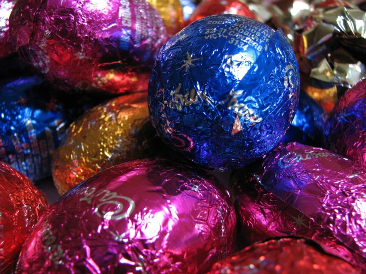 a bunch of colorful foil wrapped eggs in a pile