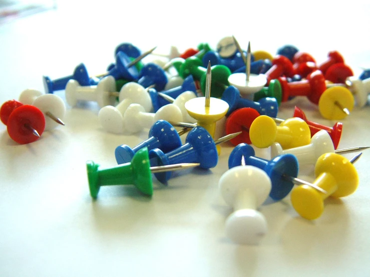 a group of pins on white table with one marked in colorful colors