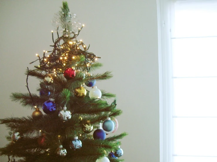 a small christmas tree with multi colored ornaments in a corner