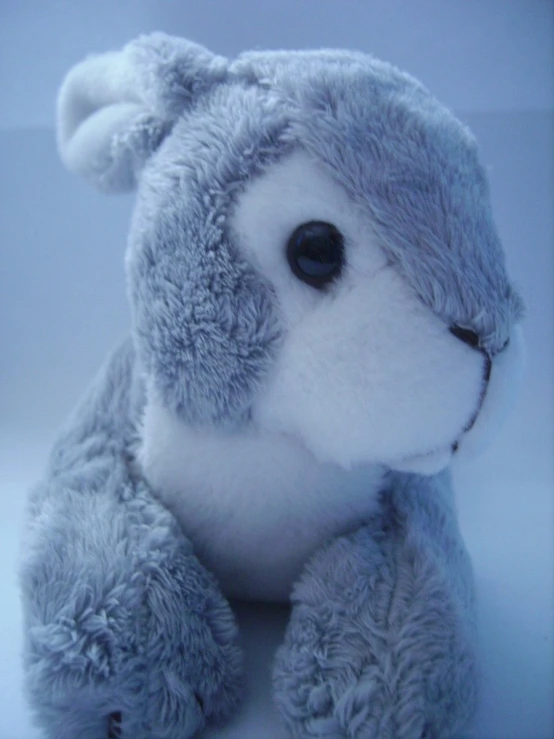 a grey stuffed animal sitting on a white surface
