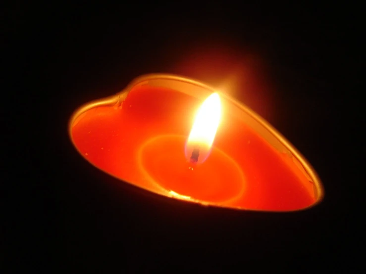 a red heart shaped candle glowing in the dark