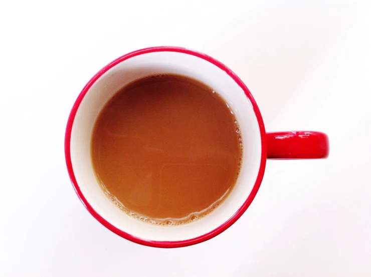 a mug filled with brown liquid sitting on top of a white table