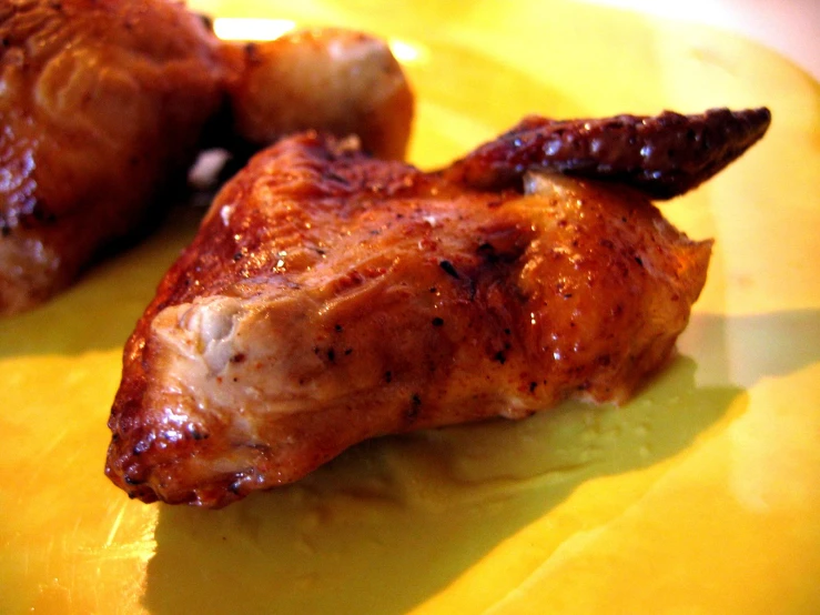 two cooked chicken pieces are on a yellow plate