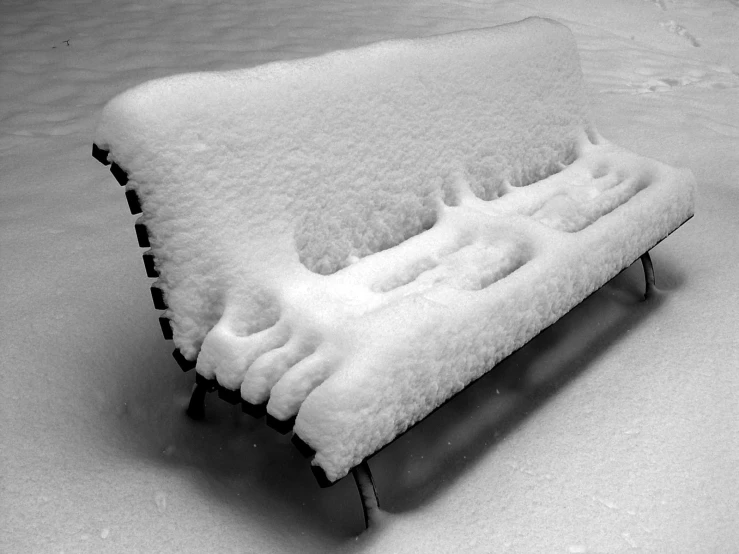 a bench that is covered in snow, sitting in the snow