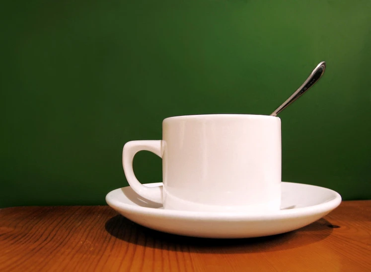 white cup and saucer on table with green background