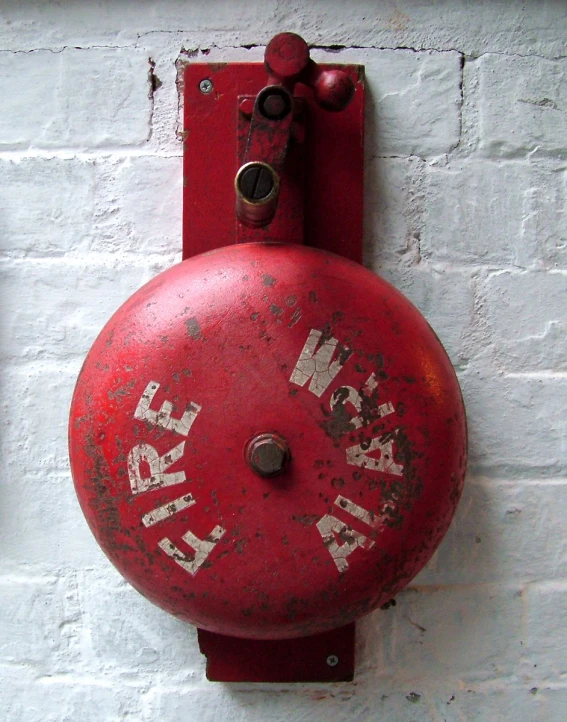 an old red fire hydrant is in front of a white brick wall